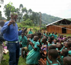 At the Nyarusunzu Primary School near the Bwindi Impenetrable National Park, Denis teaches the children about the value of forests and how they can create small forests in their local communities. Children clap with appreciation. 